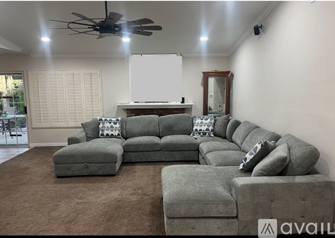 A living room with a grey sectional sofa and a whiteboard on the wall.