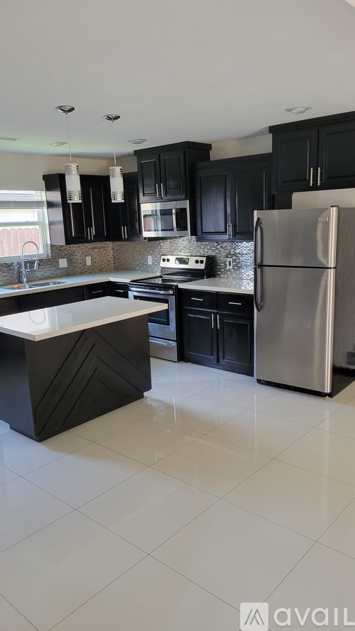 A kitchen with black cabinets and a white countertop.