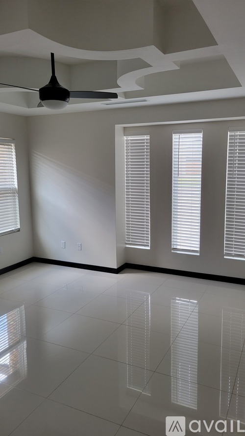 A room with a ceiling fan and windows with blinds.
