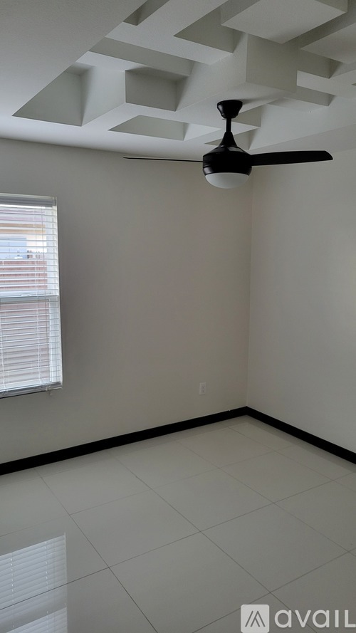 A room with a ceiling fan and a window with blinds.