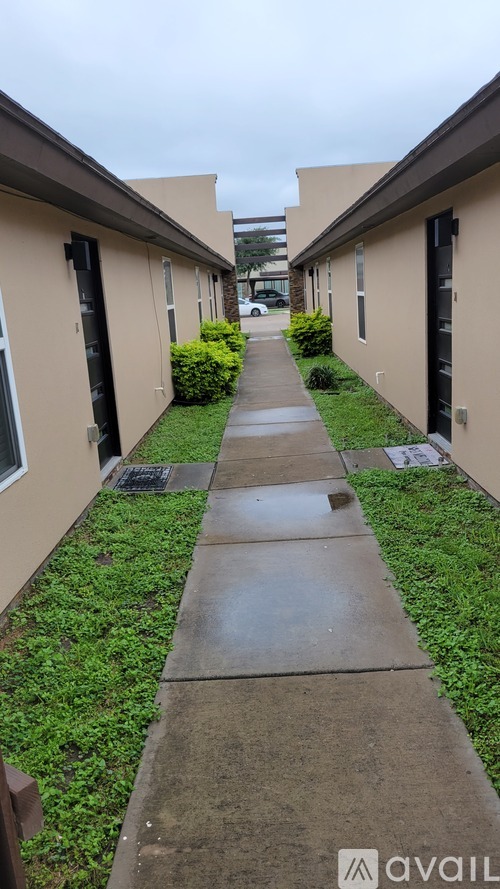 A long, narrow walkway between two buildings with greenery on the sides.