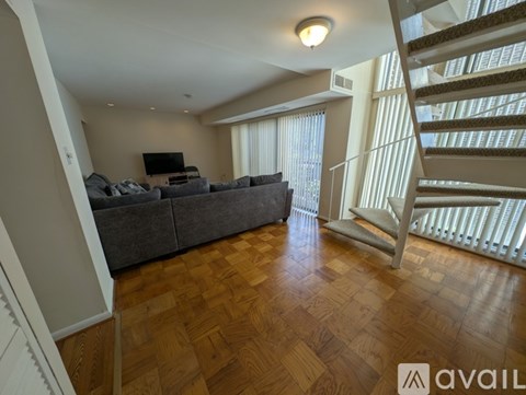 A living room with a grey couch and a wooden floor.