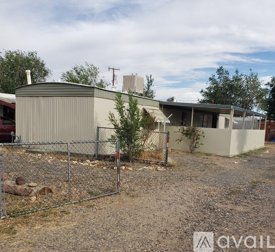 A house with a grey roof and a fence in front of it.