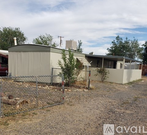 A house with a grey roof and a fence in front of it.