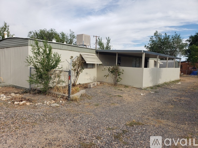 A gravel lot with a building and a tree.