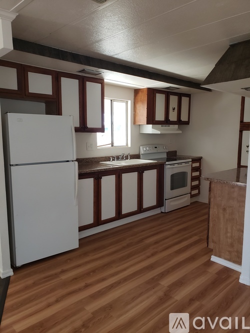 A kitchen with wooden floors and white appliances.