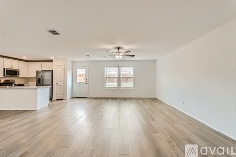 A spacious living room with a kitchen area in the background.