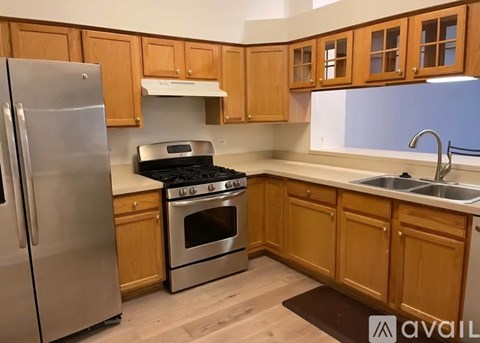 A kitchen with wooden cabinets and a stainless steel refrigerator.