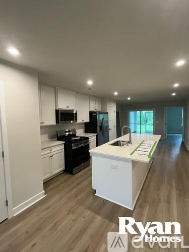A kitchen with white cabinets and a white island with a green strip on it.