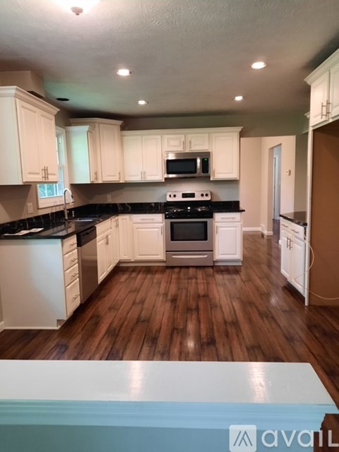 A kitchen with white cabinets and a black countertop.