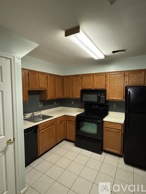 A kitchen with black appliances and wooden cabinets.