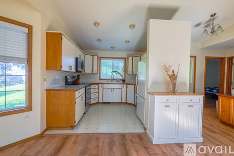 A kitchen with white cabinets and wooden floors.