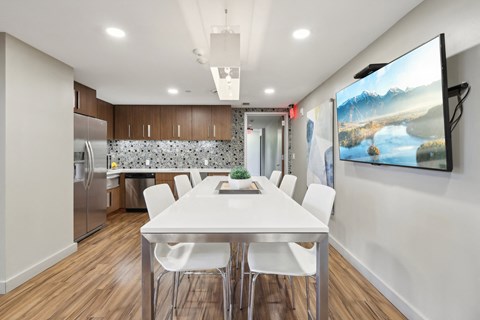 a dining room with a white table and chairs and a kitchen with stainless steel appliances