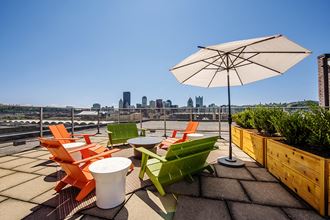 a rooftop patio with chairs and an umbrella and a city in the background