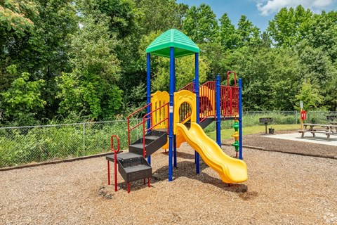 A playground with a yellow slide and a green canopy.