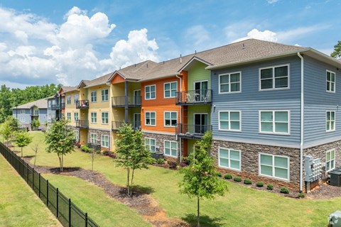 A row of multi-colored townhouses with green lawns and trees.