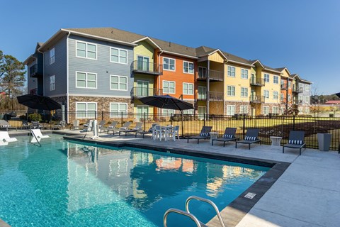 A large swimming pool in front of a multi-story apartment building.