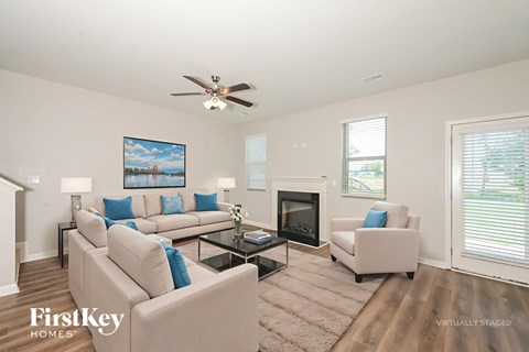 A living room with a beige couch, a fireplace, and a painting on the wall.