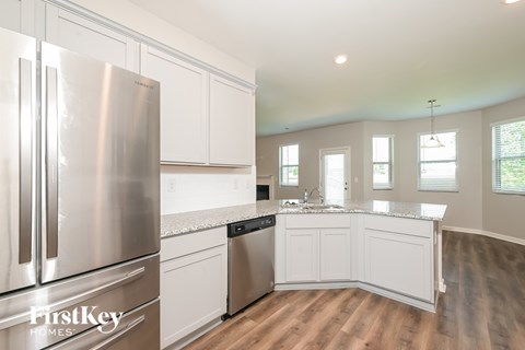 A kitchen with a stainless steel refrigerator and wooden floors.