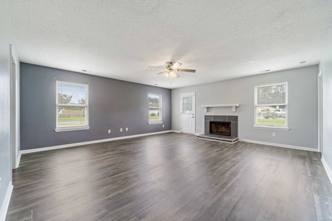 A spacious living room with a fireplace and a ceiling fan.