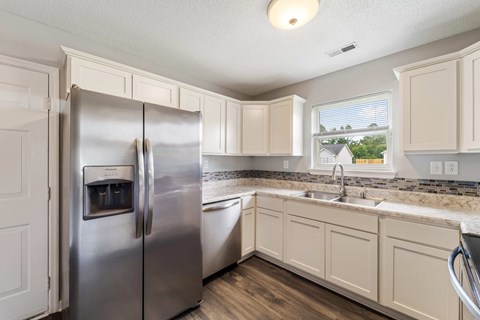 A kitchen with a stainless steel refrigerator and white cabinets.