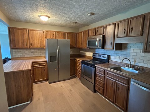 A kitchen with wooden cabinets and a refrigerator.