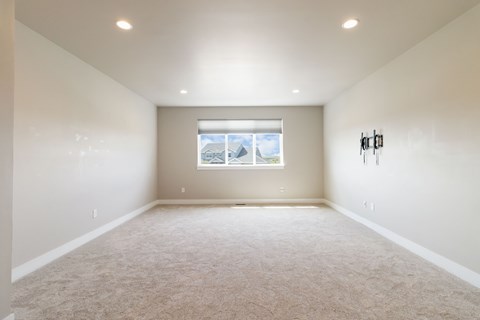A spacious room with a window and carpeted floor.