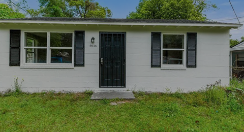 A small white house with a black door and windows.