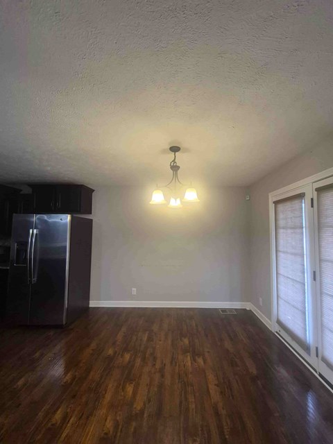 A kitchen with a refrigerator and a chandelier.