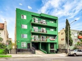 A green building with a balcony on the second floor.