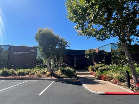 A building with a sign that reads "4.611" is surrounded by trees and plants.