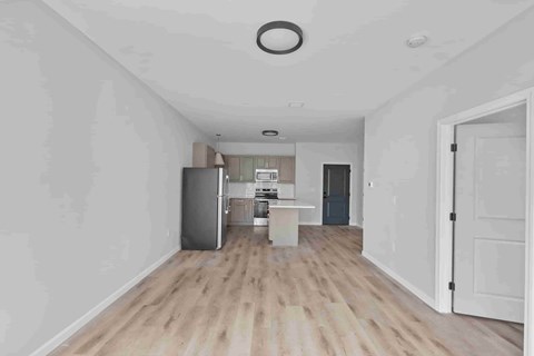 A kitchen with a refrigerator, sink, and cabinets is visible through an open door.