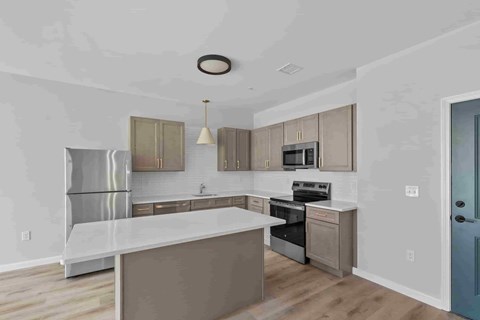 A modern kitchen with a large island and stainless steel appliances.