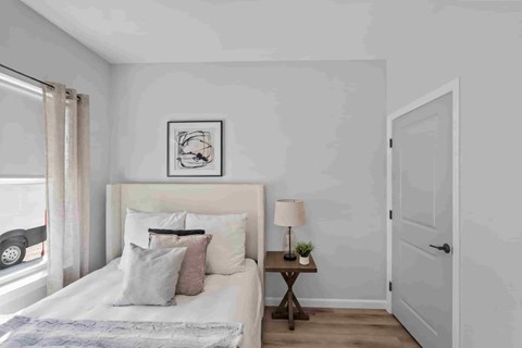 A bedroom with a bed, nightstand, and a painting on the wall.