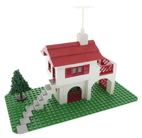 A white and red house with a green tree and a white chimney.