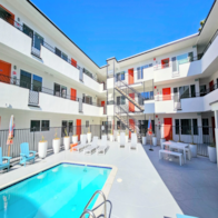 A swimming pool in front of a white building with orange and blue accents.