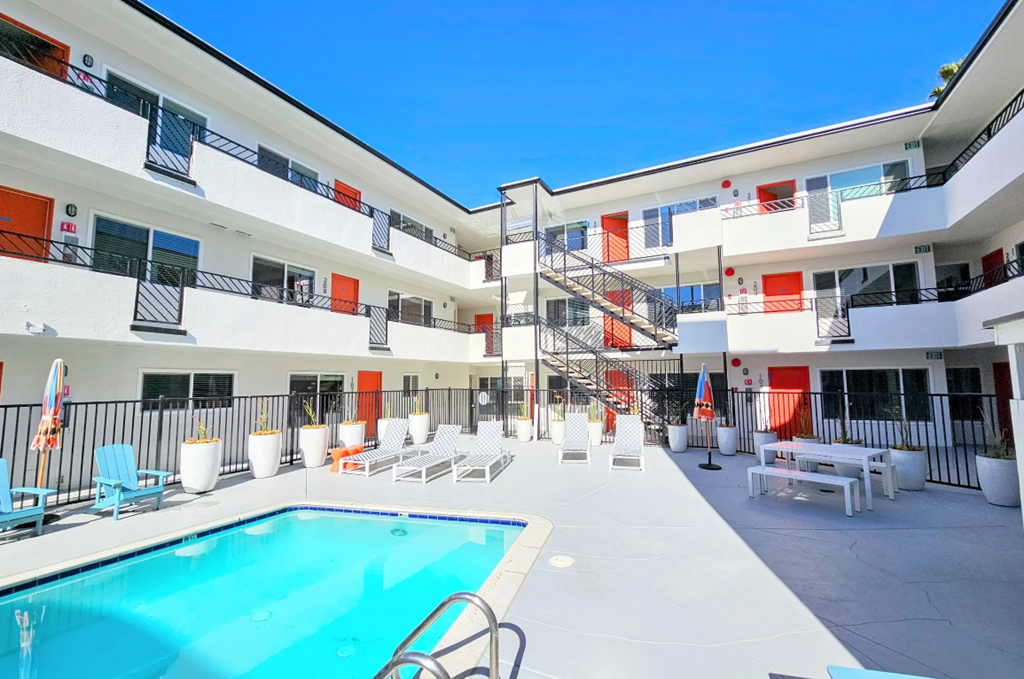 A large white building with orange trim and a pool in the middle.