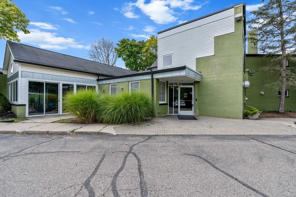 A modern two-story house with a green exterior and a grey roof.