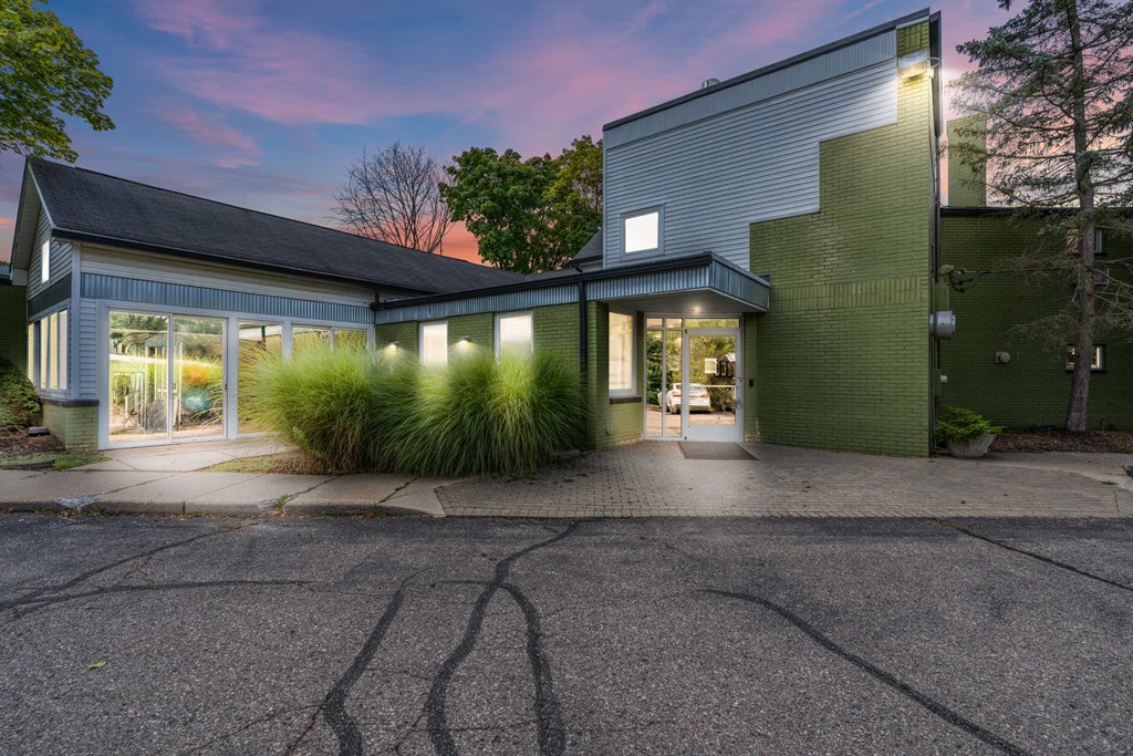 A modern house with a green wall and a grey roof.