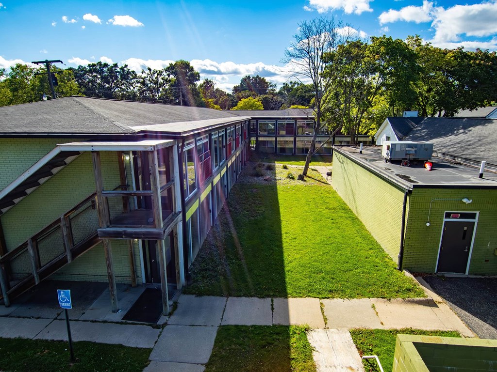 A sunny day at a residential area with a green lawn and a building with a balcony.