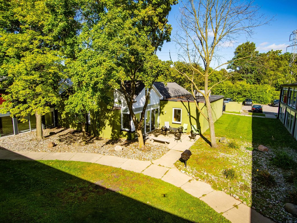 A house with a green lawn and trees in front.