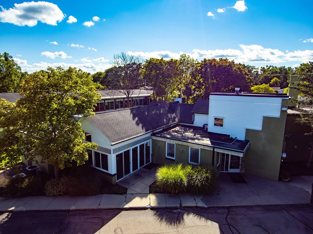 A house with a white exterior and a grey roof is surrounded by trees.