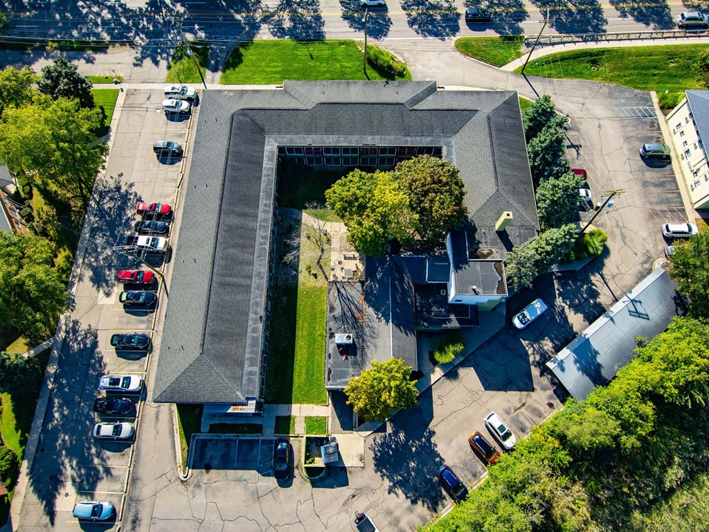 A large building with a grey roof is surrounded by a parking lot.
