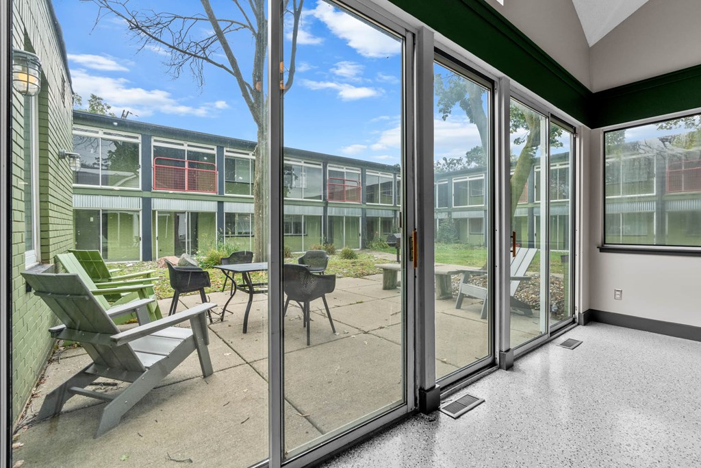 A patio with chairs and a table is visible through a glass door.