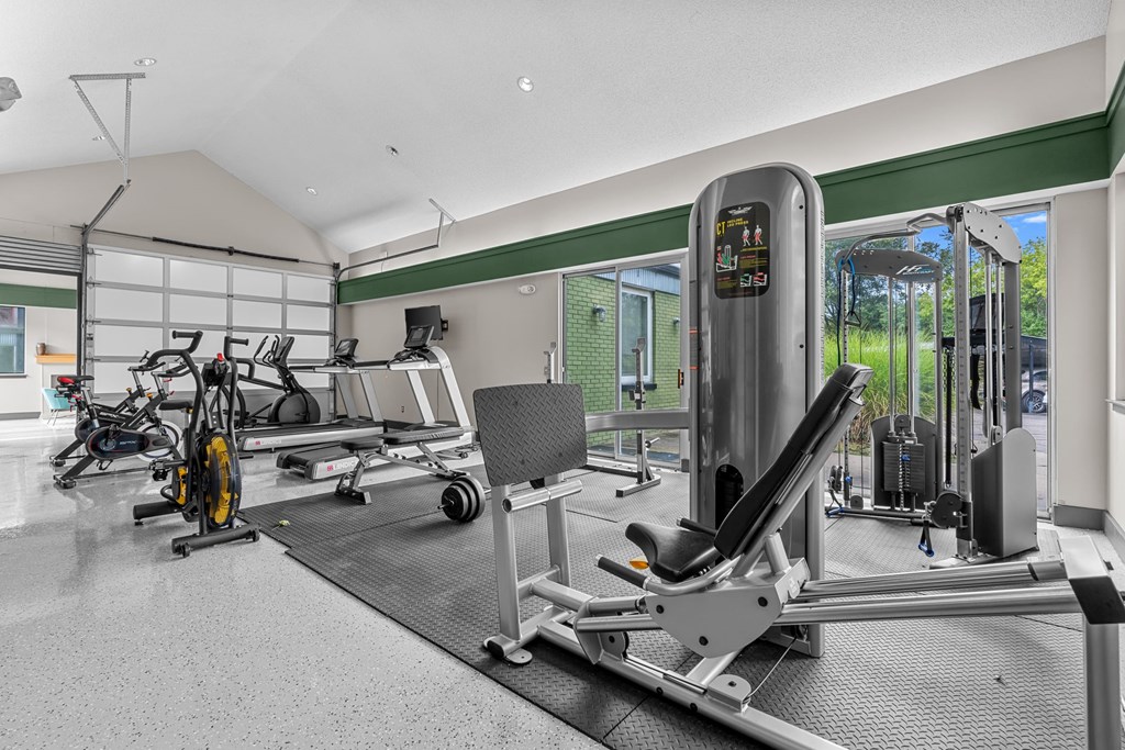 A gym with a variety of equipment including a treadmill, a stationary bike, and a rowing machine.