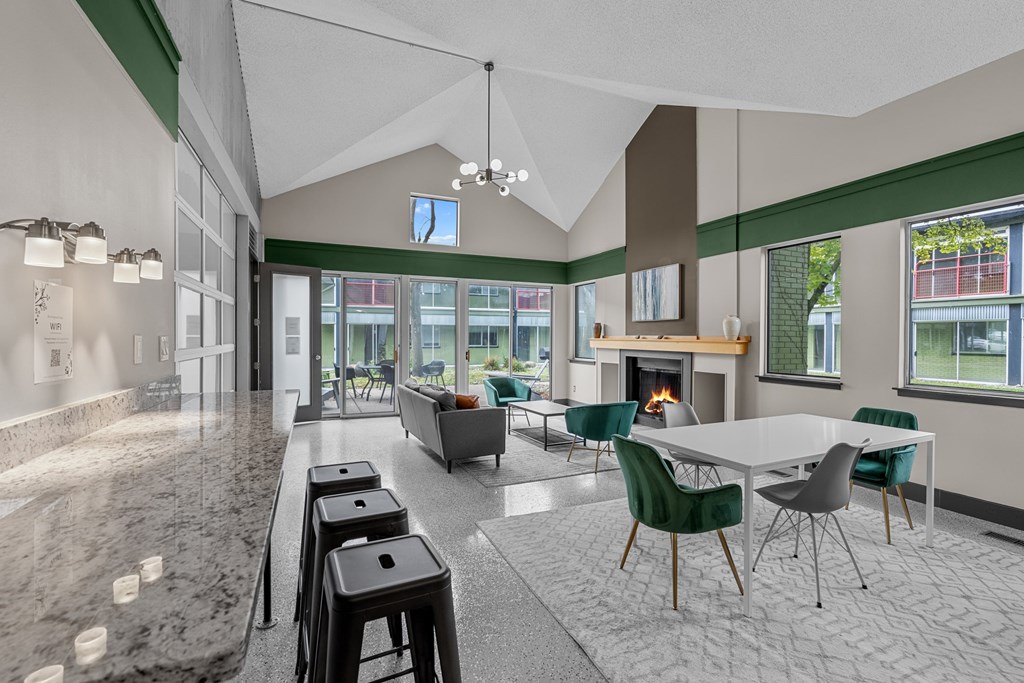 A modern kitchen with a marble countertop and a dining area with green chairs.