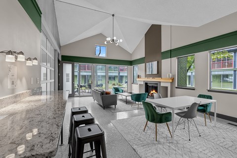 A modern kitchen with a marble countertop and a dining area with green chairs.