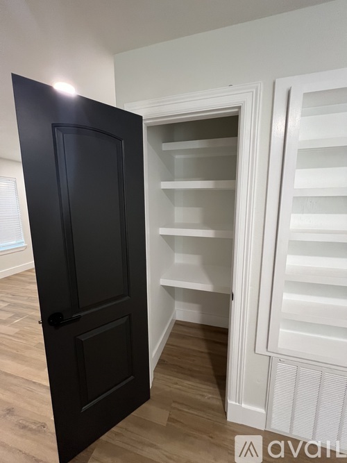 A black door is open to a white interior.