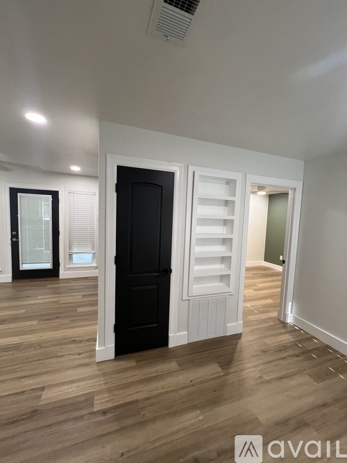 A room with a black door and wooden flooring.