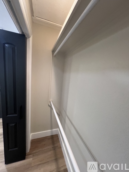 A hallway with a black door and white walls.